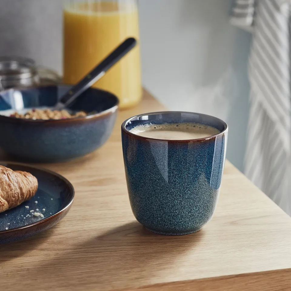Blue ceramic mug on wooden table with croissant and cereal bowl, part of the GLADELIG series.