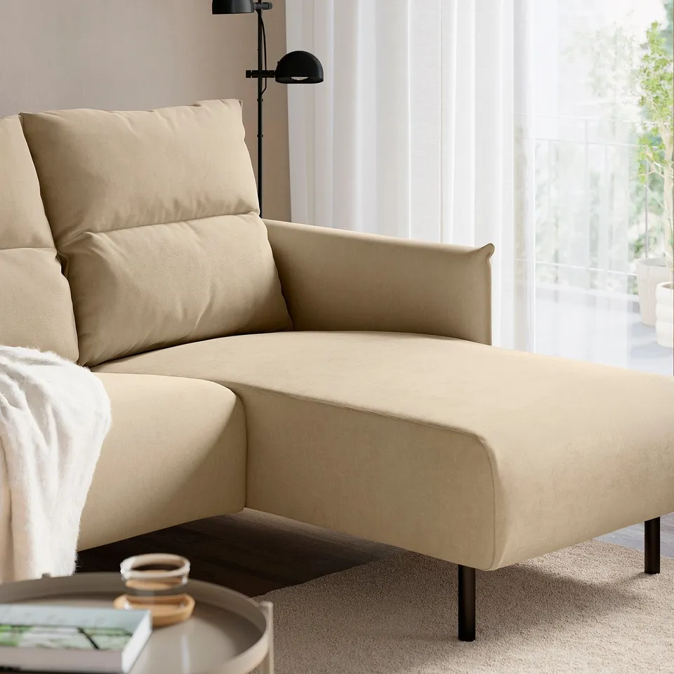 Neutral-colored sectional sofa with high backrest and chaise. Modern, comfortable with a cup and magazine on side table.