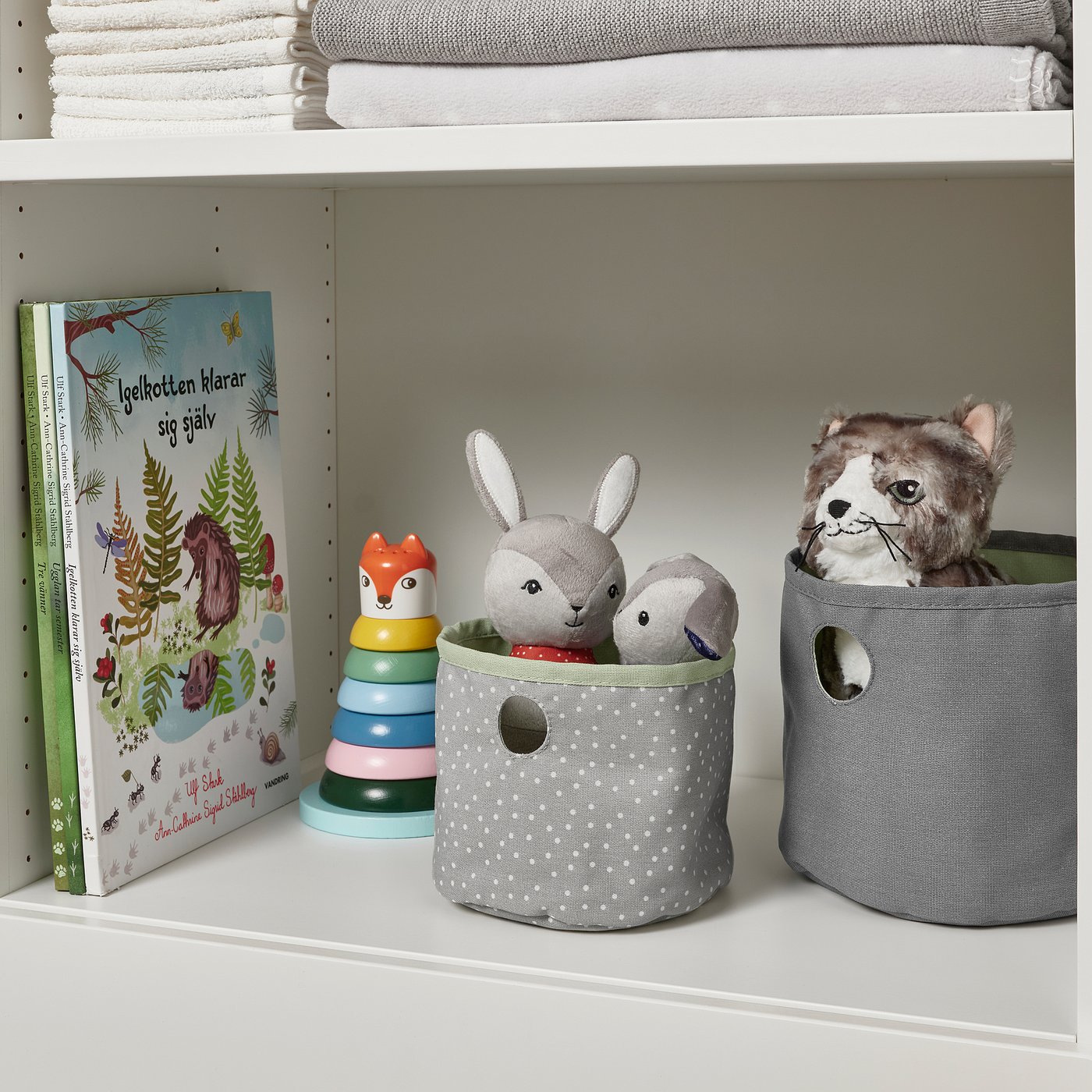 Shelf with colourful toy blocks, stuffed animals, and storage bins for kids items.