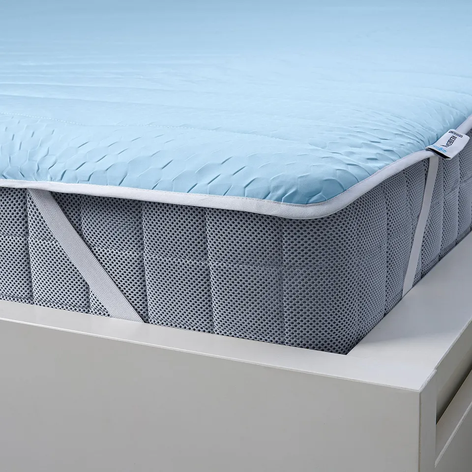 Blue mattress protector with mesh sides, fits white bed, cool comfort.