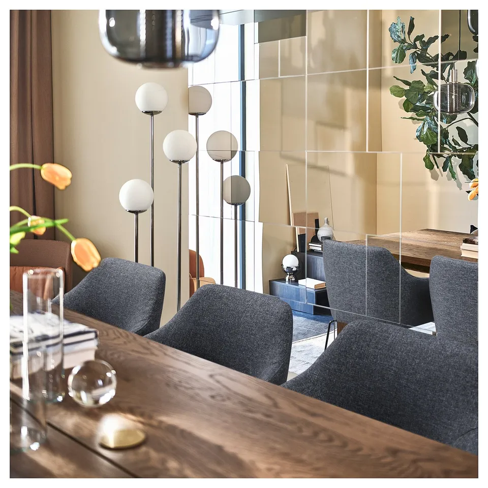 Modern dining set with dark wood table, grey upholstered chairs, spherical pendant lights, and clear dividers.