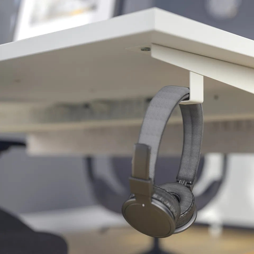Headphones hang on adjustable desks hook.