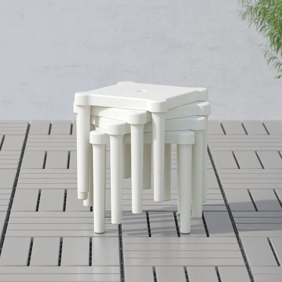 White plastic stools stacked together, suitable for kids play areas.