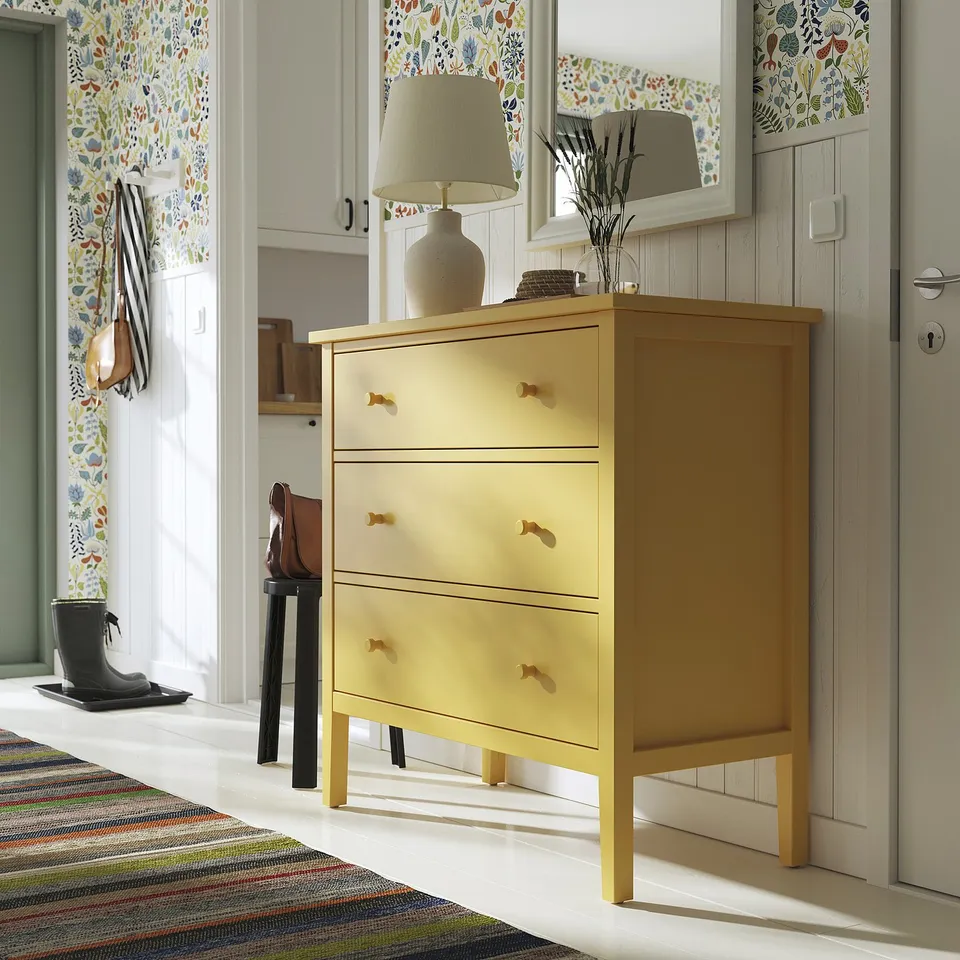 Yellow GULLABERGer dresser with handles, lamp, vase, mirror, black boots.
