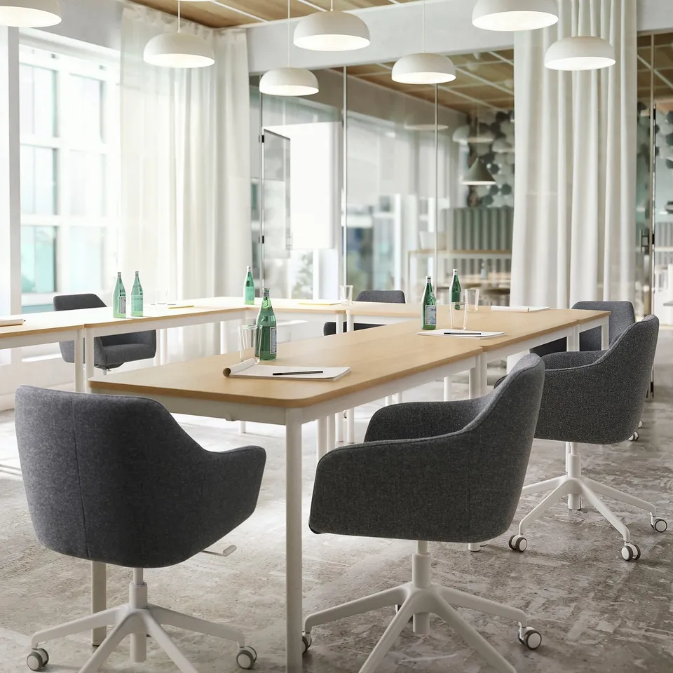 Modern office with wooden tables, grey swivel chairs, green bottles, white curtains, and hanging lights.
