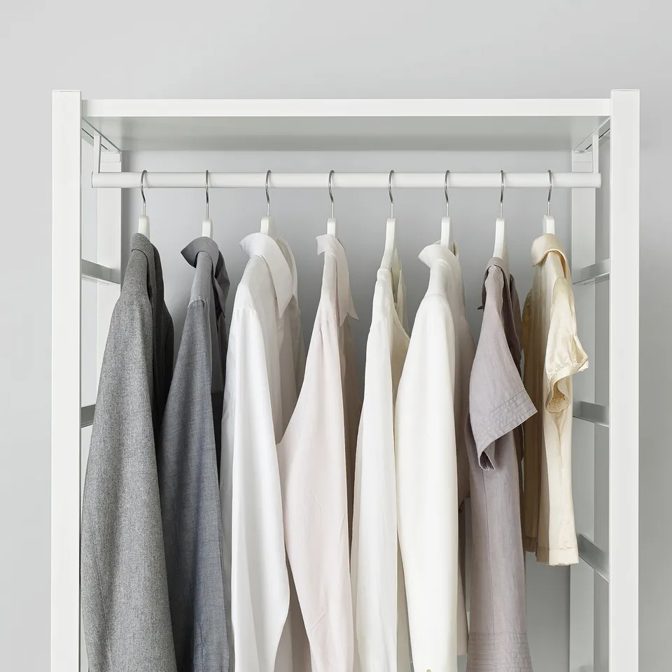 ELVARLI closet showing adjustable shelves and hanging rail with neatly organised clothes in various shades of grey and white.