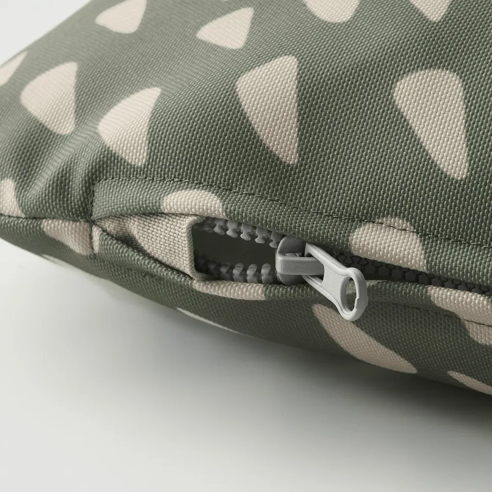 Close-up of a cushioned pet bed with a green and white geometric pattern, featuring a durable zip pull.