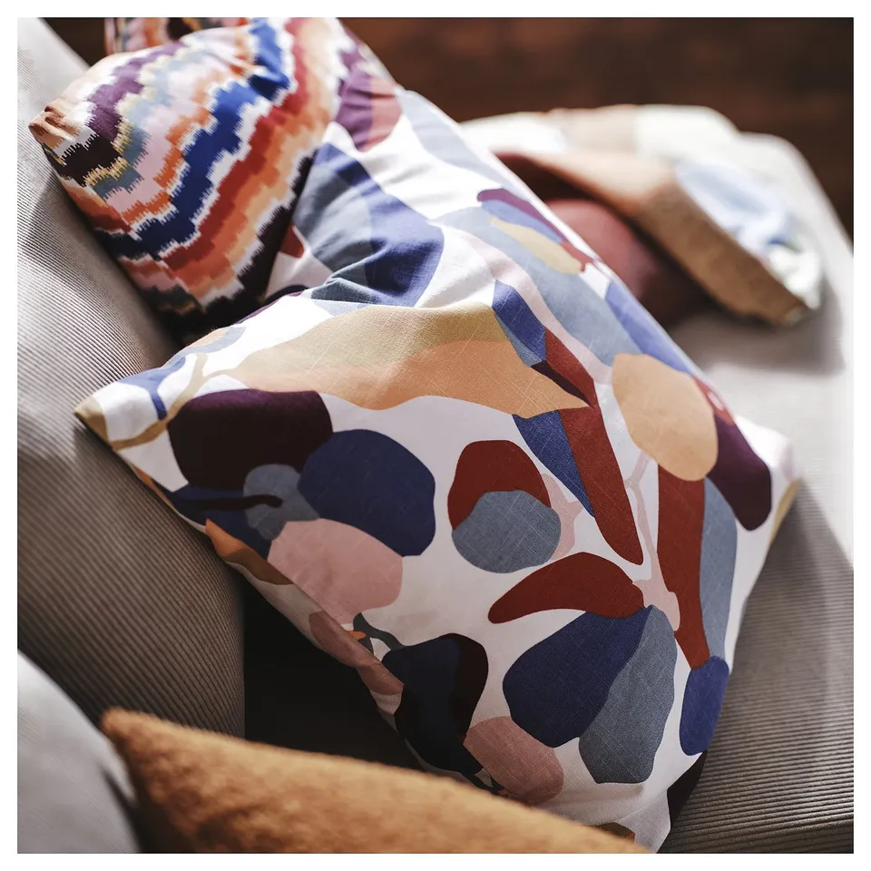 Colourful throw pillows on couch, abstract shapes and patterns in earth tones, soft decorative cushions.