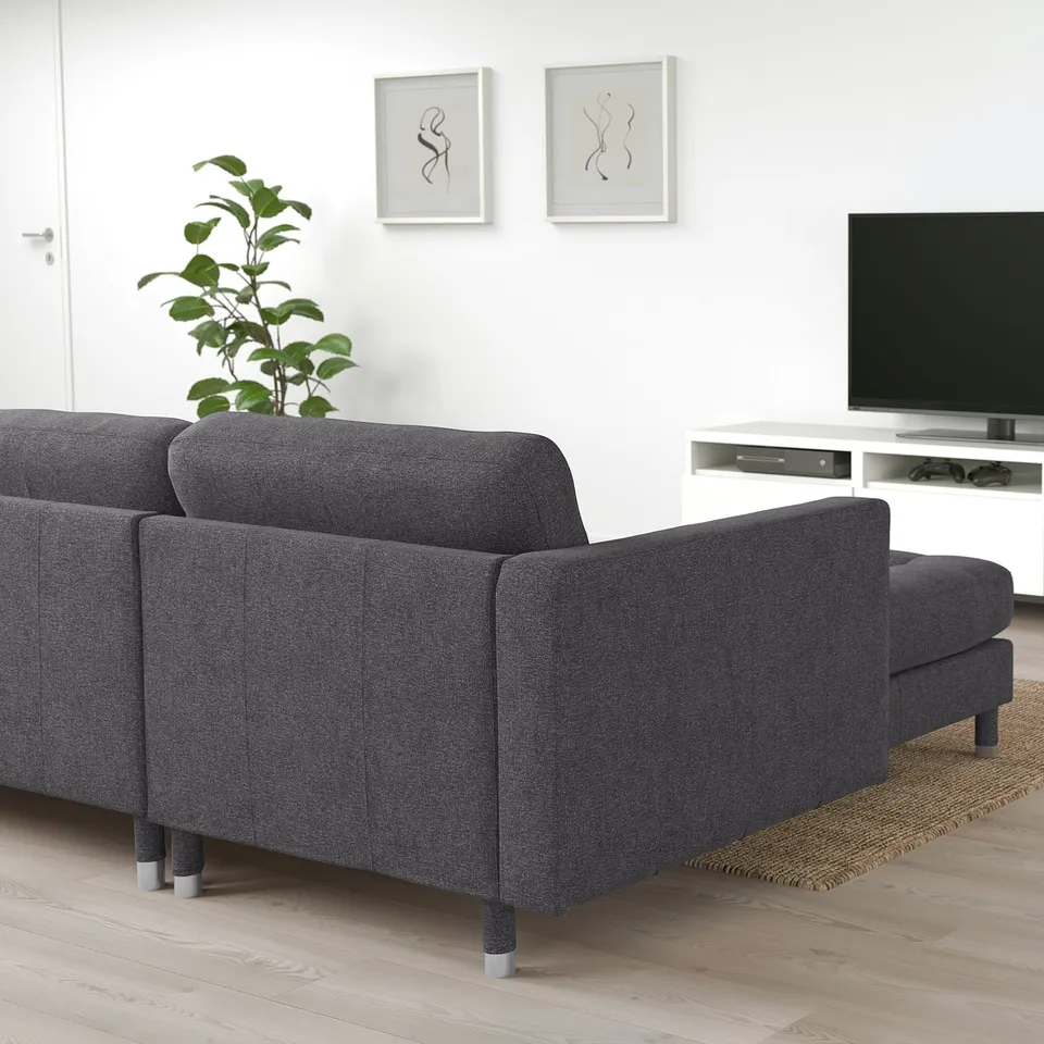 Dark grey LANDSKRONA l-shaped sofa in minimalist living room, with tv and plant nearby.