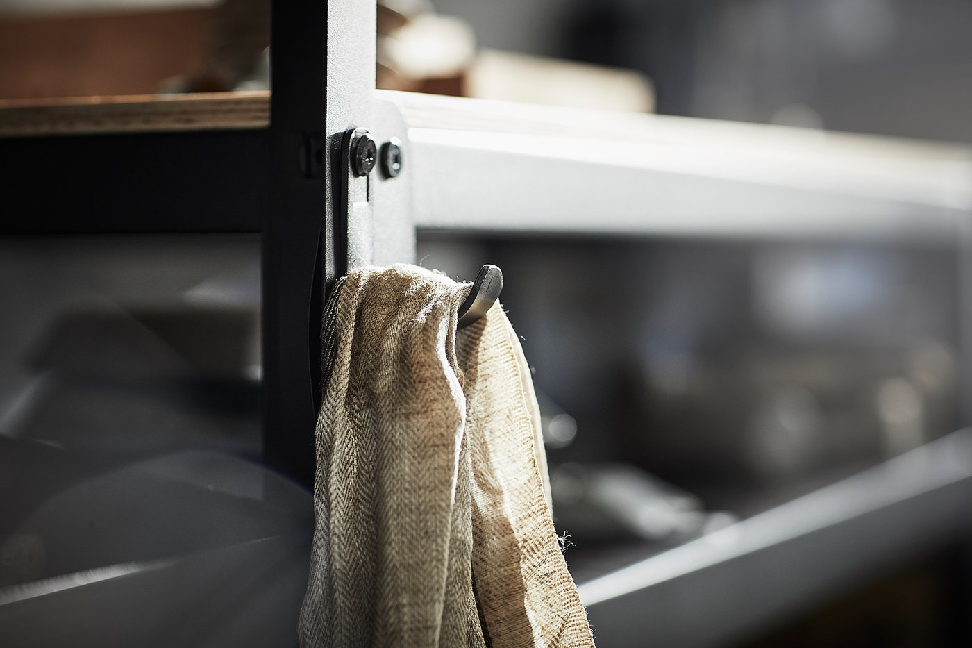 A BROR black metal hook holding a beige cloth, on a sturdy storage system.
