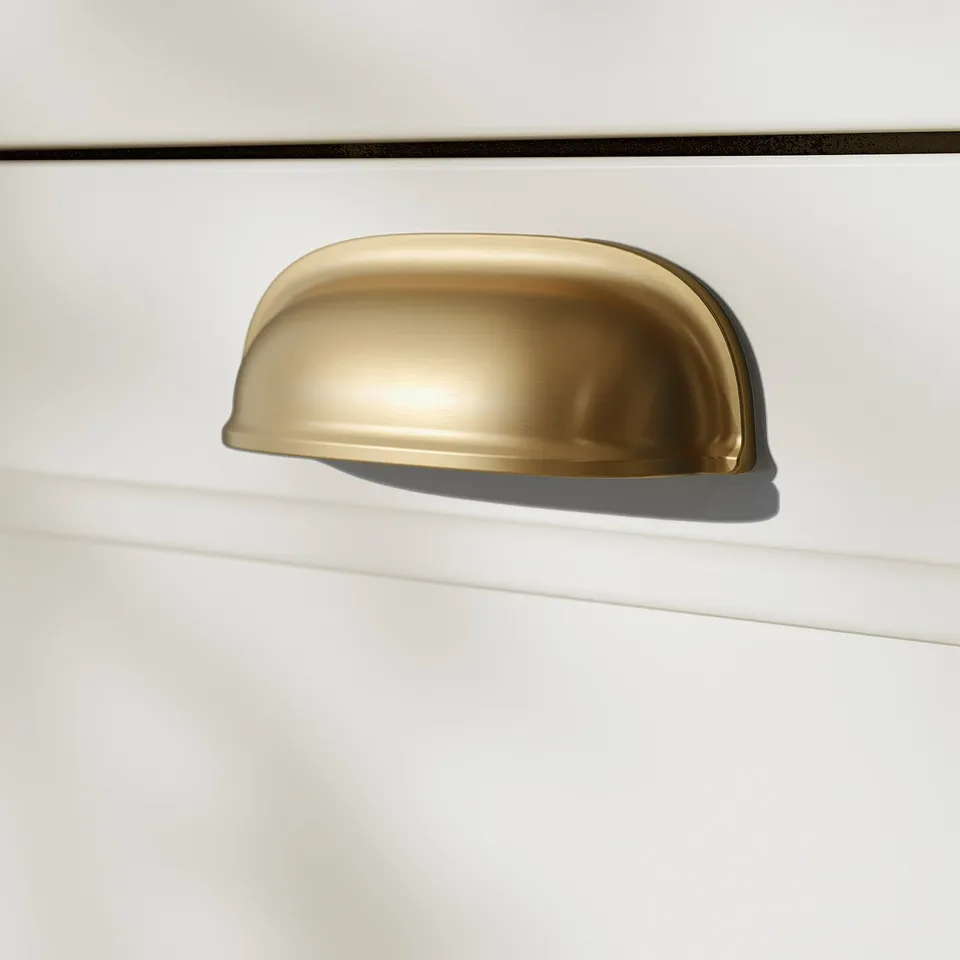 Golden drawer handle on white cabinet. Smooth, sleek design.