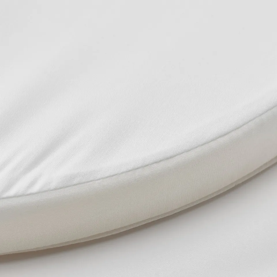 Circular, white baby mattress with smooth, adjustable fabric and simple design.
