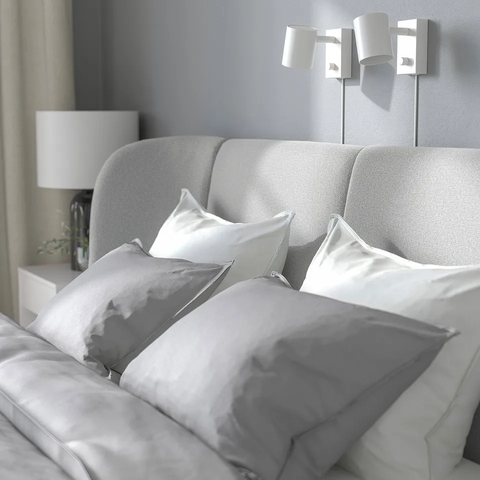 Grey plush bed with curve headboard, soft lights.