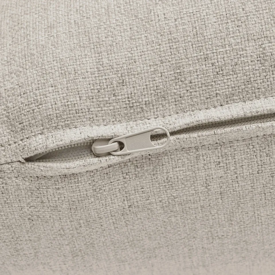 Close-up of zip on light grey upholstered cushion, showcasing quality fabric and seamless detailing.