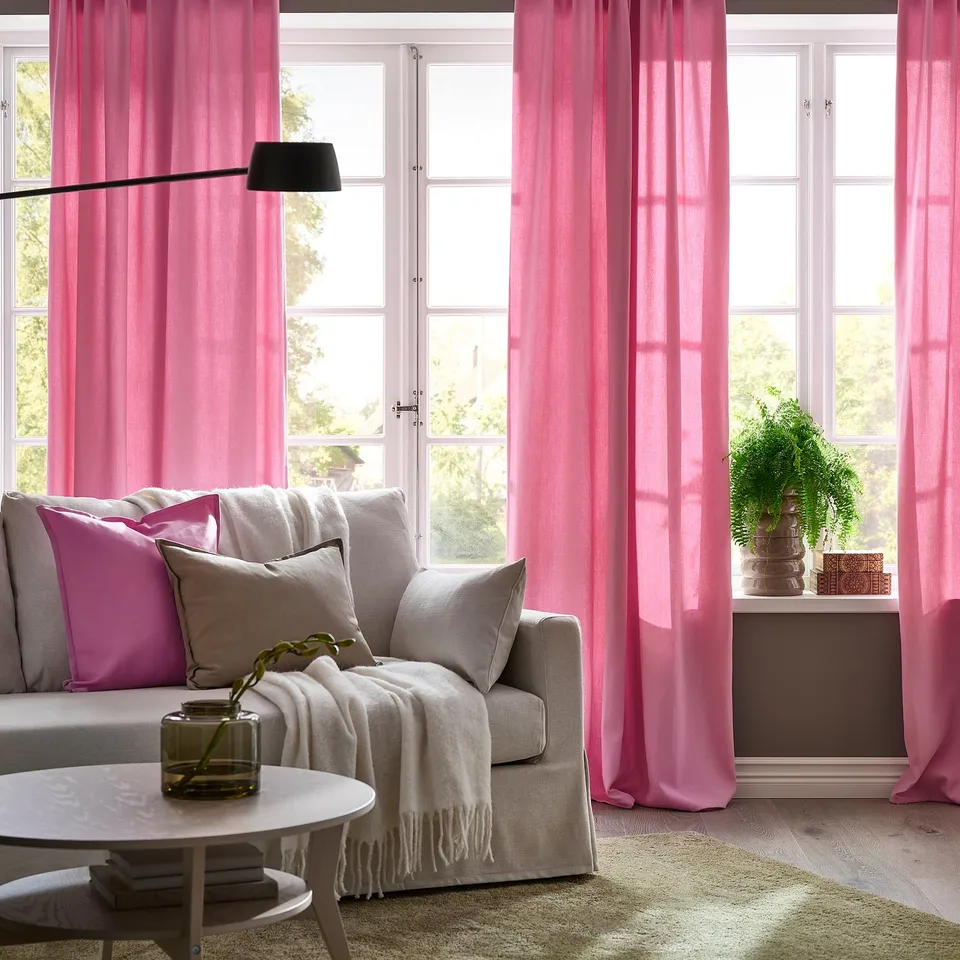 Pink curtains & grey sofa in cosy living room with minimalist coffee table.