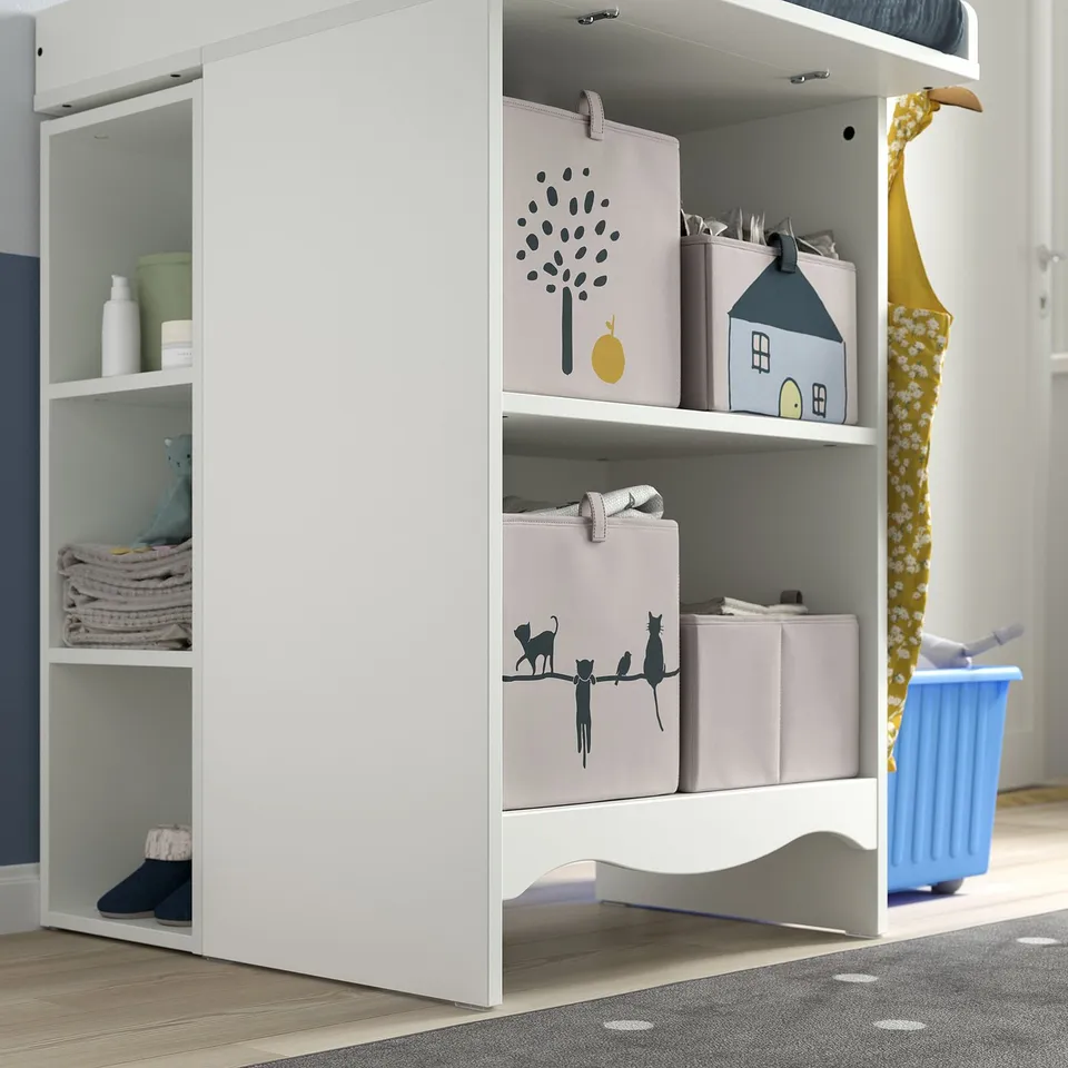 White changing table shelf with storage boxes and folded clothes.