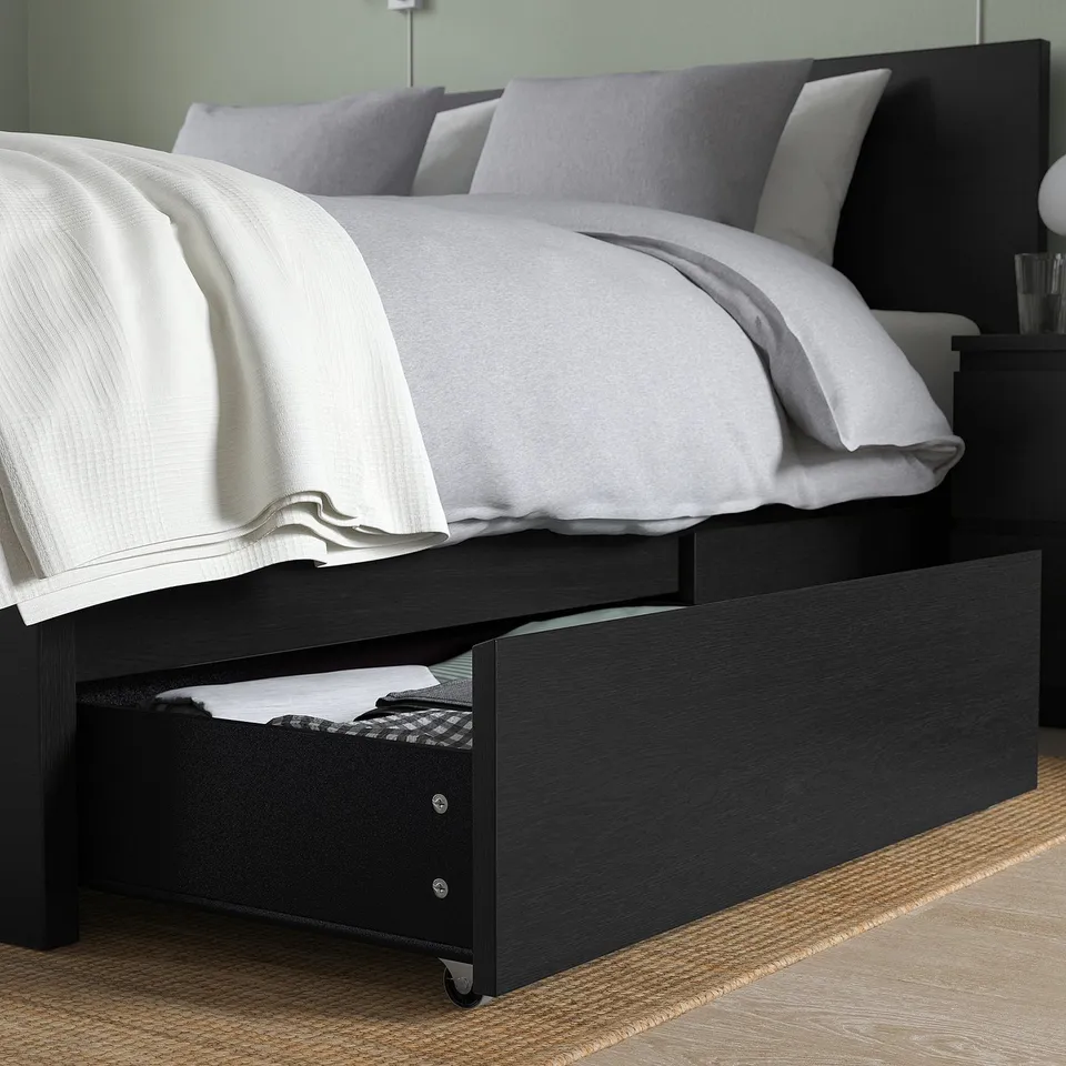 Bed with drawers under frame for storage, light wood, grey bedding.
