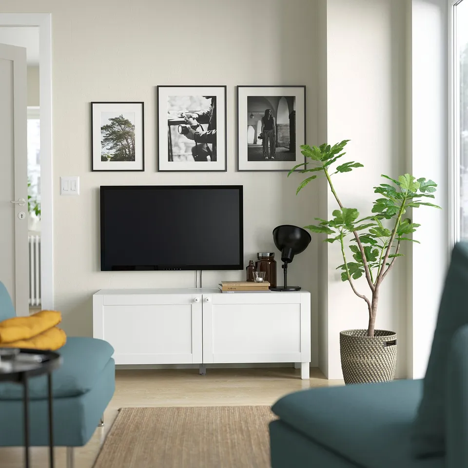 Modern living room with tv, photos, blue chair, wood table, and plant.