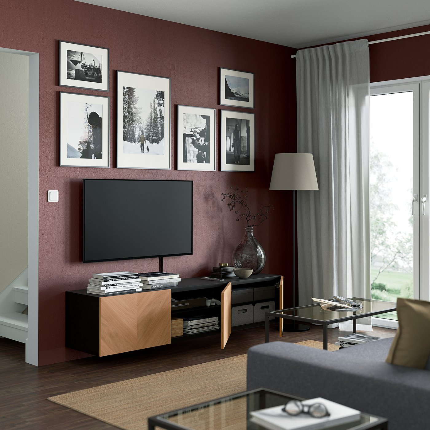 Modern living room with maroon walls, featuring a wall-mounted BESTÅ tv bench with adjustable shelves, cable management, and a soft-close mechanism.
