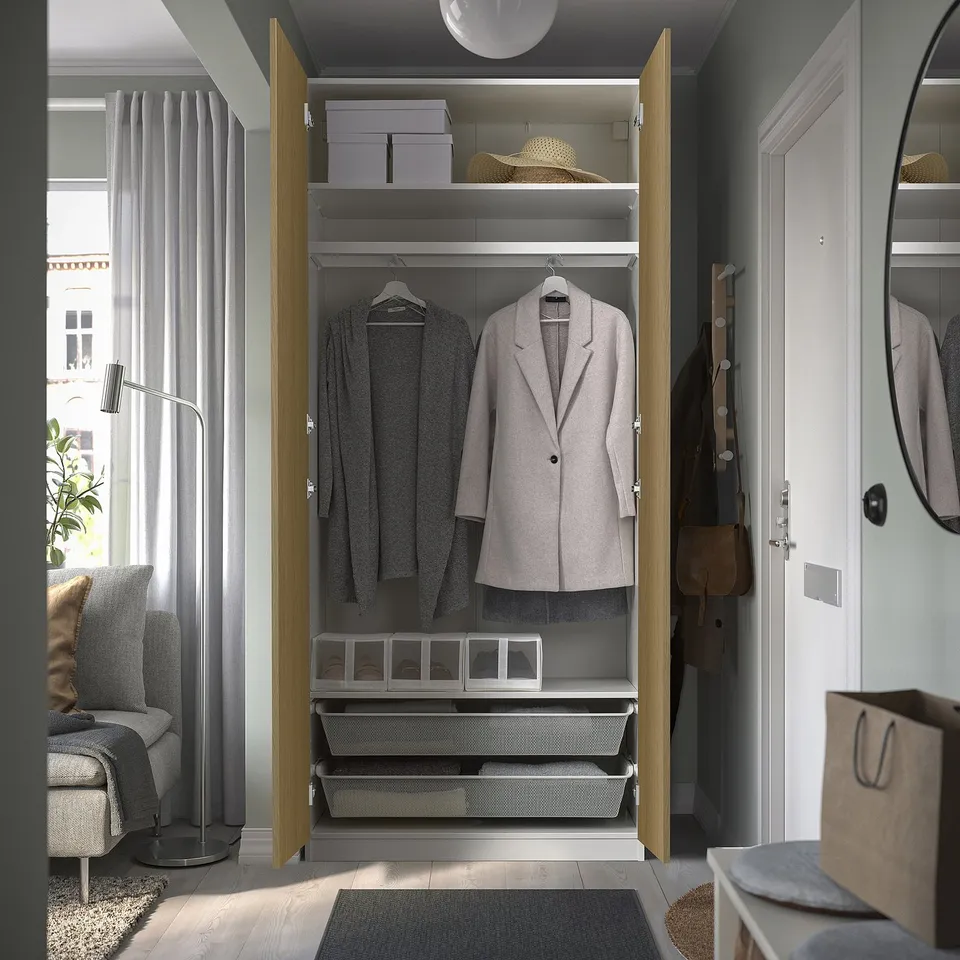 Open closet displaying coats and storage bins, with modern room decor in background.