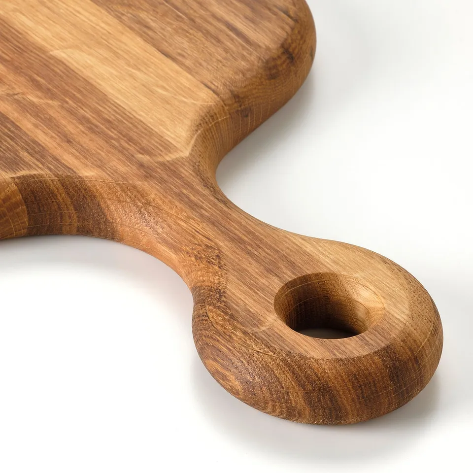 Oval wooden cutting board with handle, crafted from solid oak, shown against a white background.