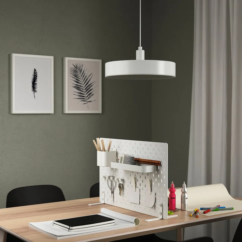 Modern home office with SKÅDIS pegboard, office supplies, plant art, pendant light, and workspace essentials.
