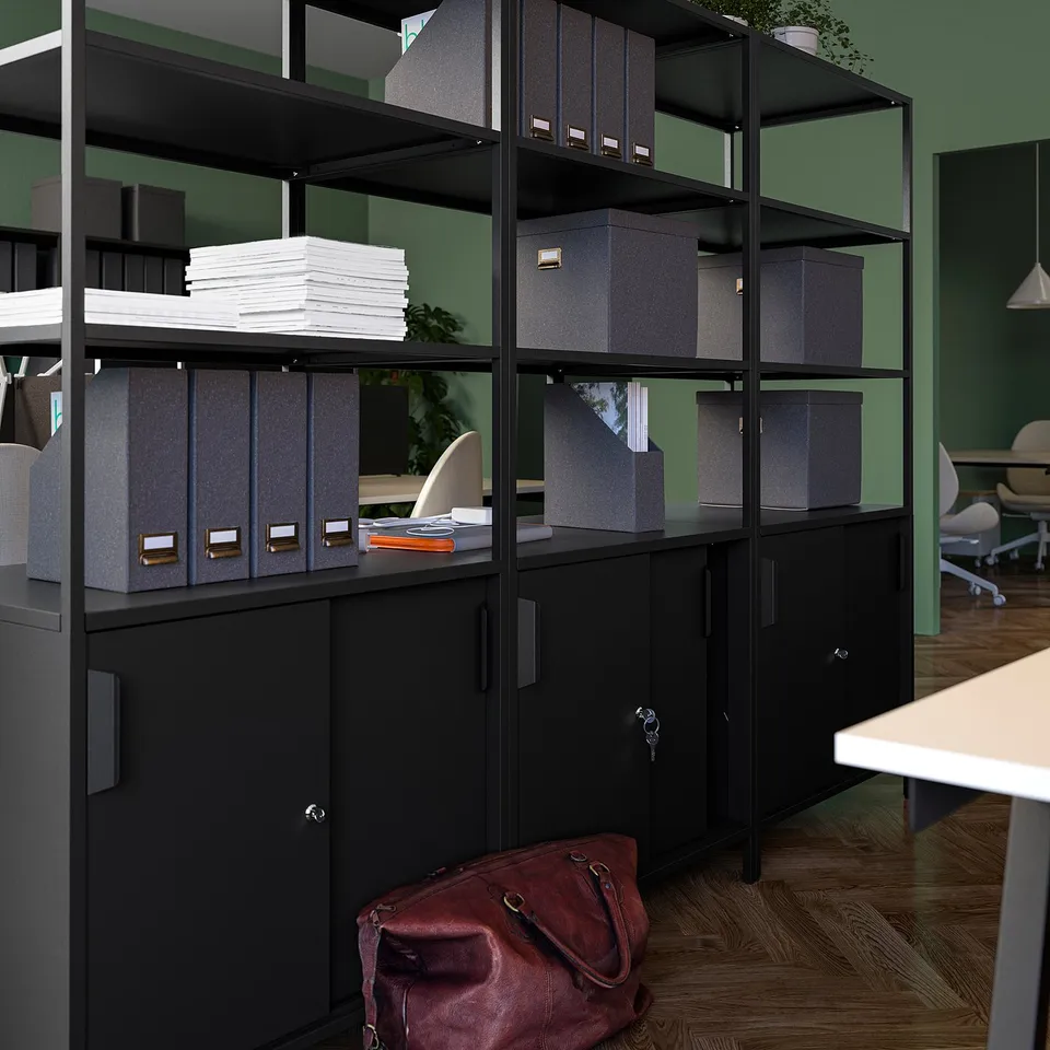 Black office storage unit with open and closed shelves, holding files, books, and a bag on the floor. Ideal room divider.
