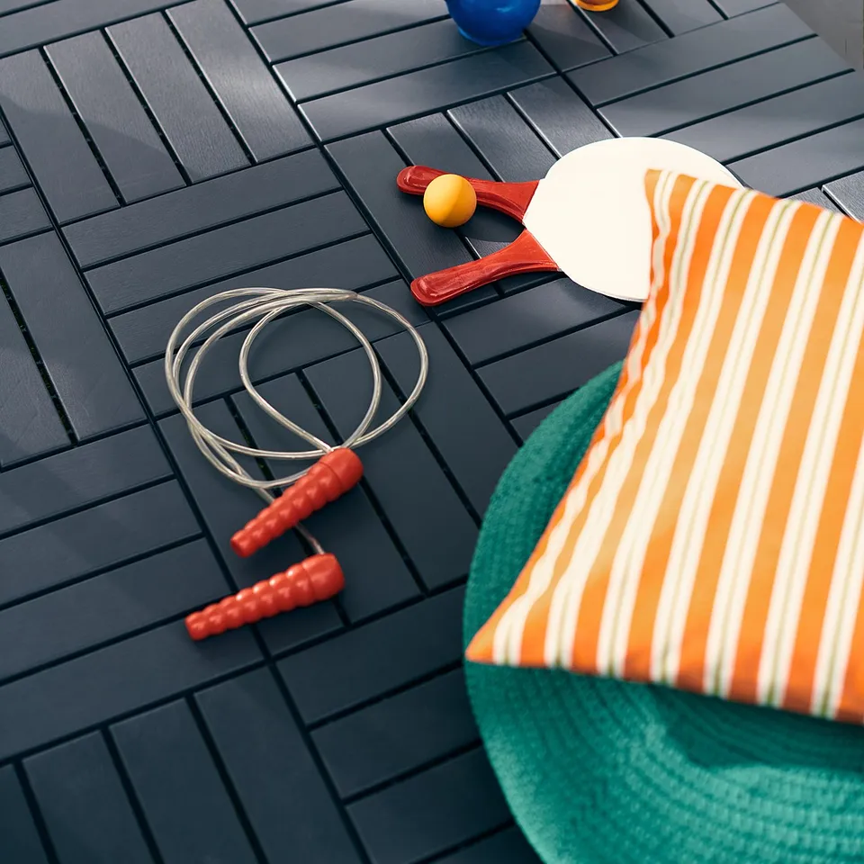 Grey RUNNEN deck tiles with exercise gear and striped pillow.
