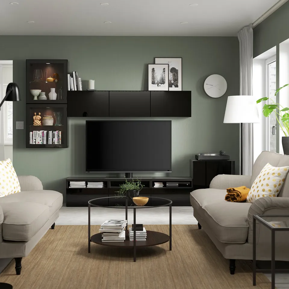 Modern living room with sage walls, BESTÅ tv unit, grey sofas, and a stylish clock.
