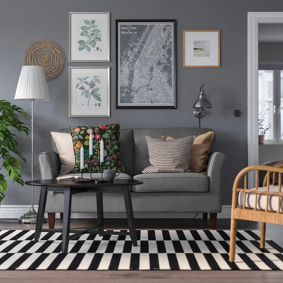 Modern living room with grey couch, colourful pillows, striped rug, coffee table, gallery wall, lamp, and rocking chair.