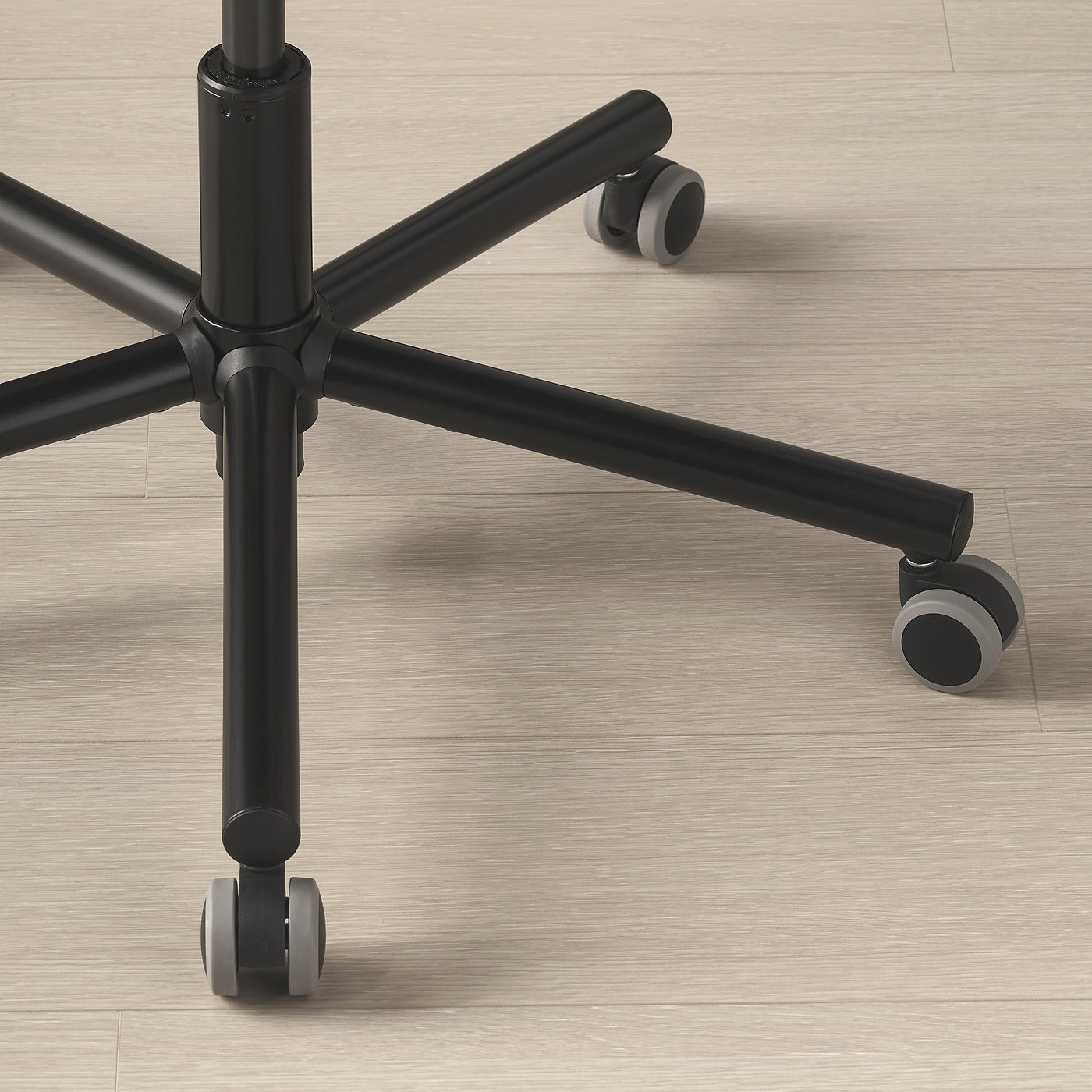 Chair base with sturdy metal frame and smooth wheels on wooden floor.