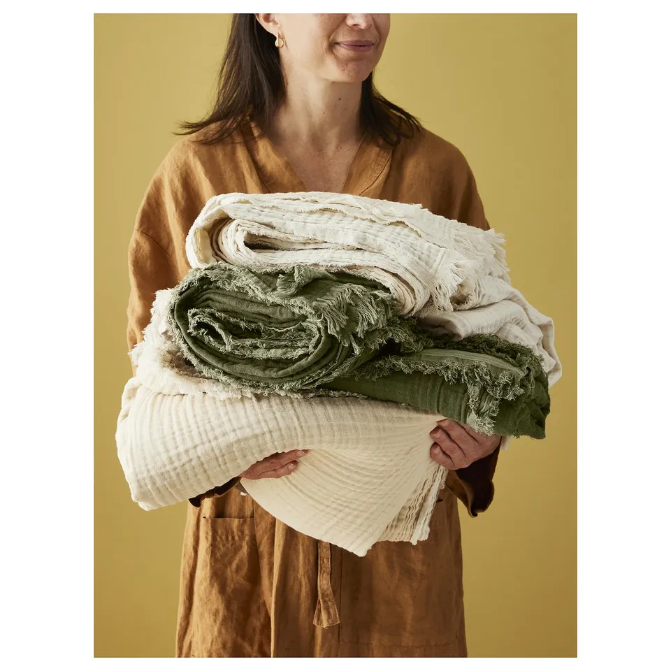 A person holding rolled towels in beige and green.