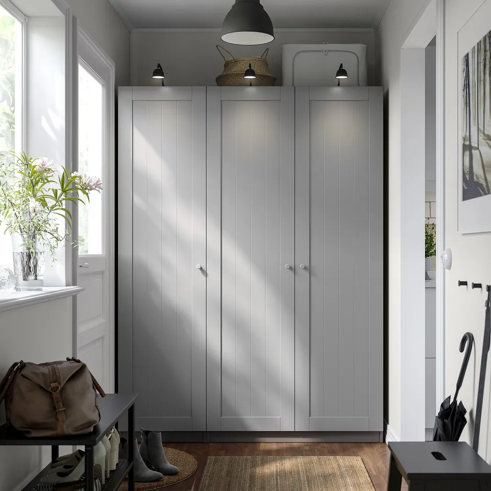 Modern entryway with PAX wardrobes, lamp, and bench under a window with plants.