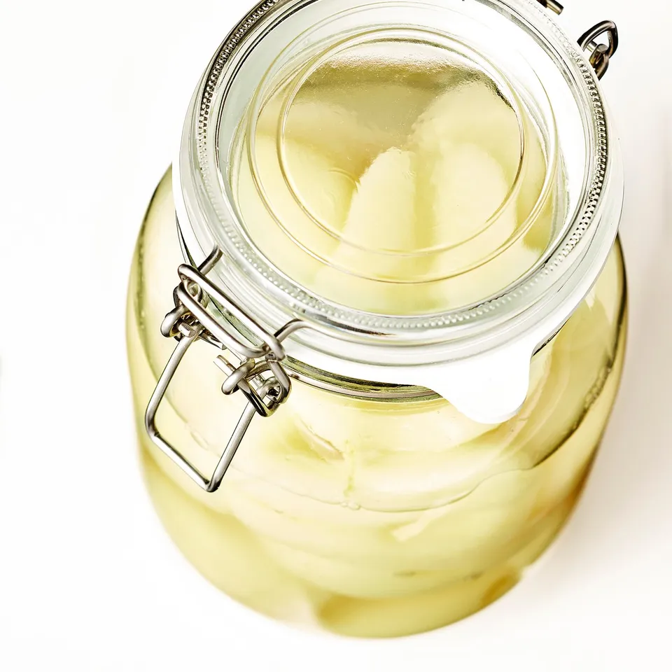 Glass jar with metal clasp and seal, designed for pickling and preserving, ensuring airtight storage.
