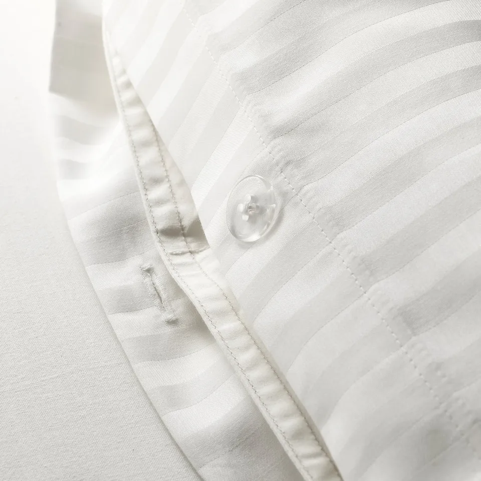Close-up of high-quality duvet cover with subtle stripes and smooth button.
