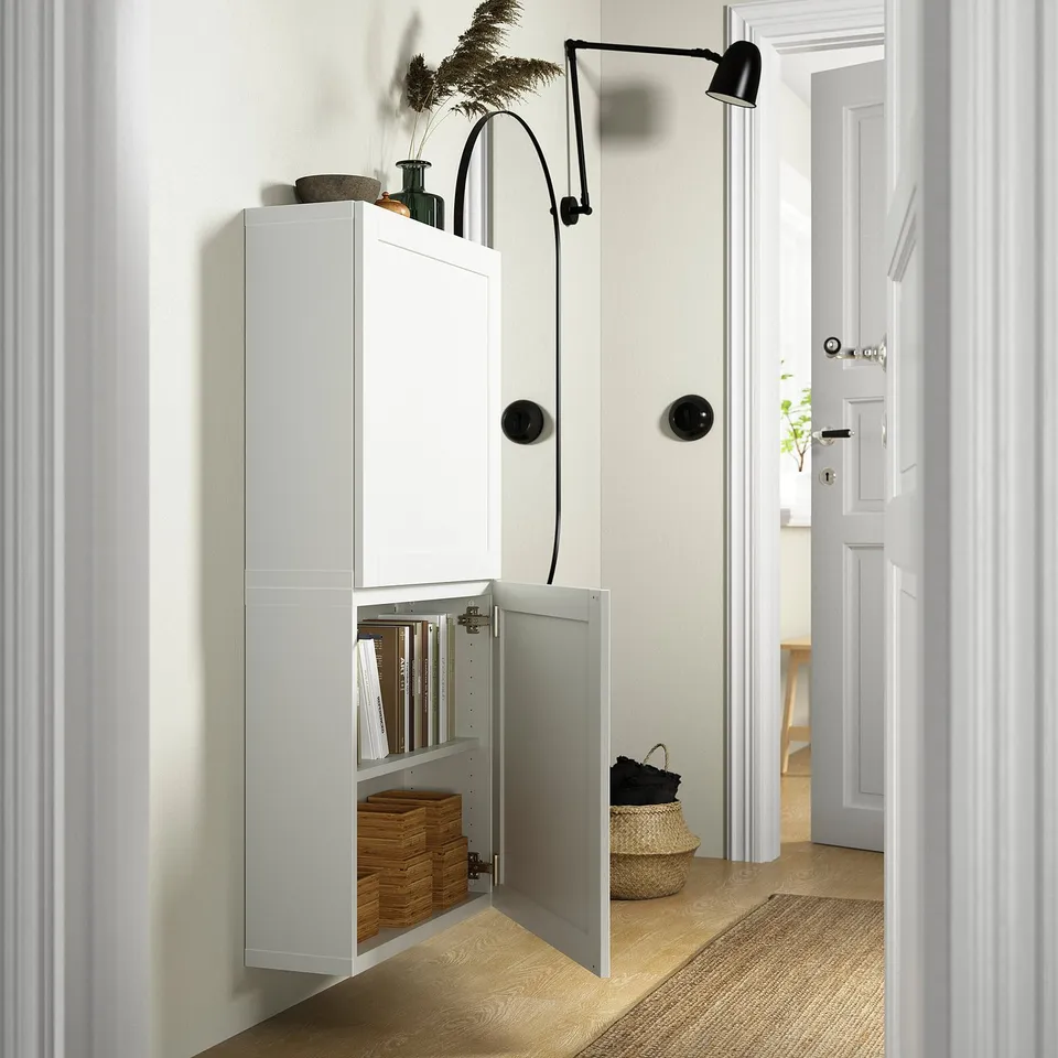 White BESTÅ cabinet open showing organised storage with books and wicker basket. Adjustable shelf and push-open door function.