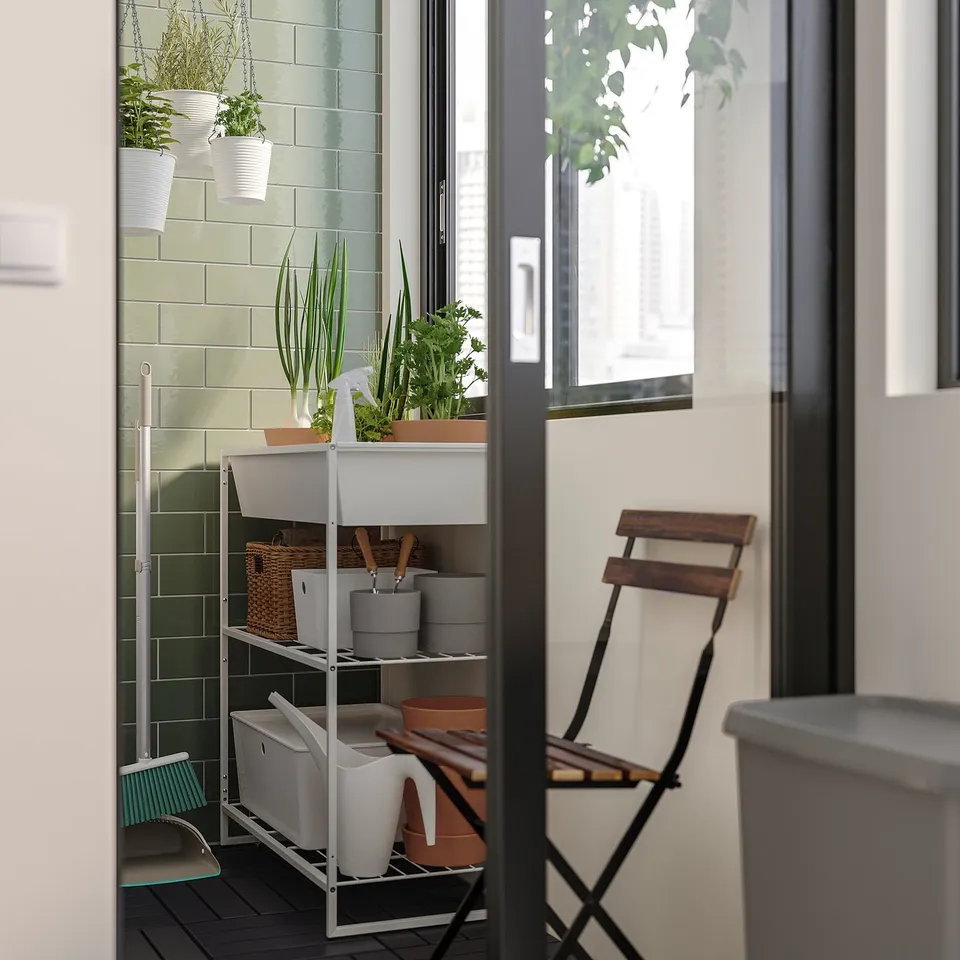 Small balcony with JOSTEIN white storage, green plants, and black chair.
