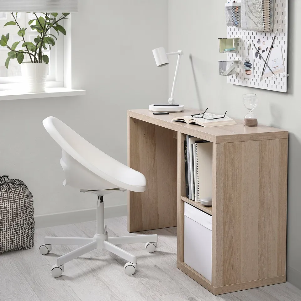 Minimalist home office with KALLAX desk, chair, lamp, plant, cable outlet.