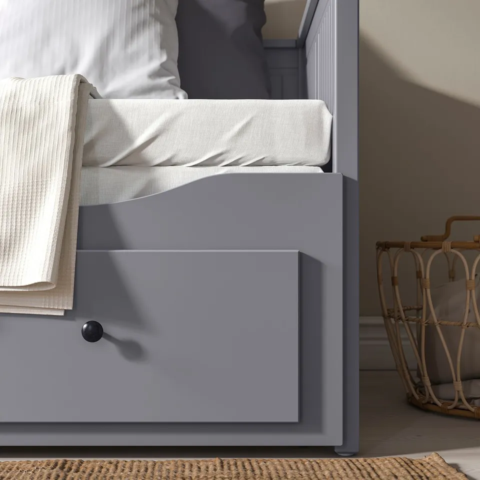 Grey daybed with drawers and folded white blanket, demonstrating its dual use as a comfortable seating area or sleeping space.