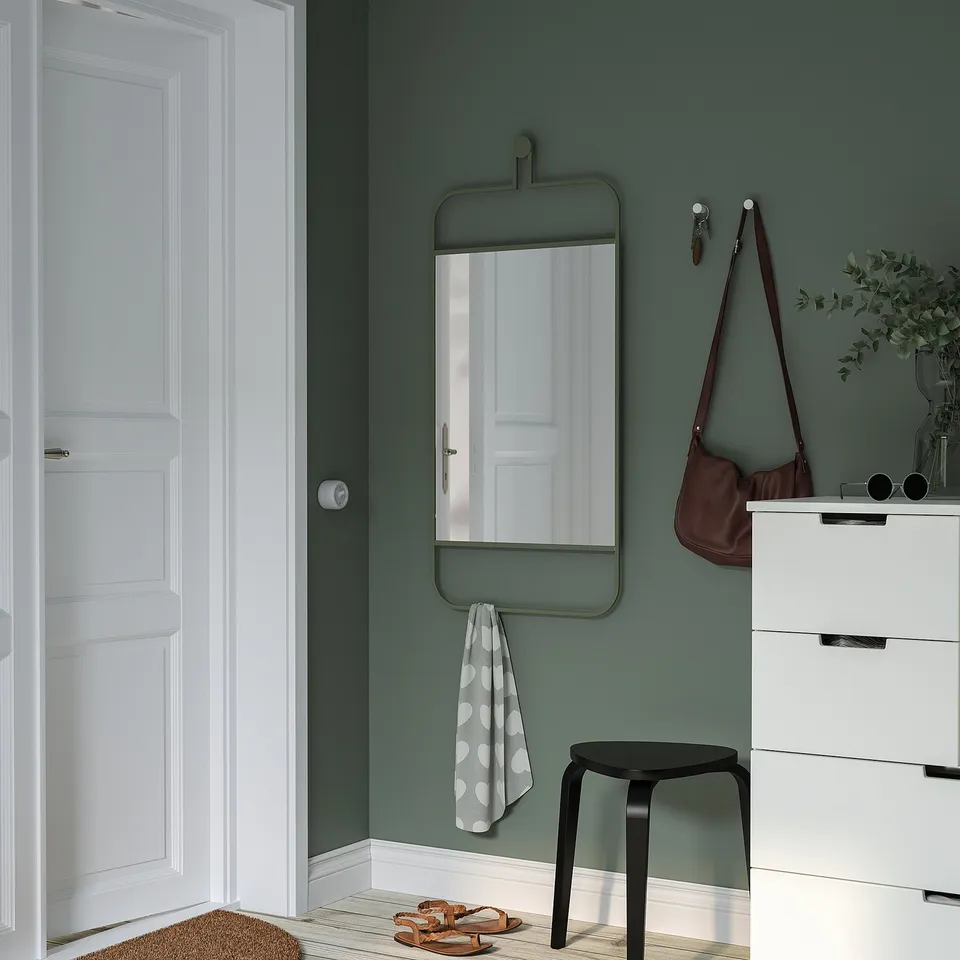 Green GRANVÅG mirror in hallway, reflects door, with hooks. Nearby: white dresser, bag, stool, polka dot towel.