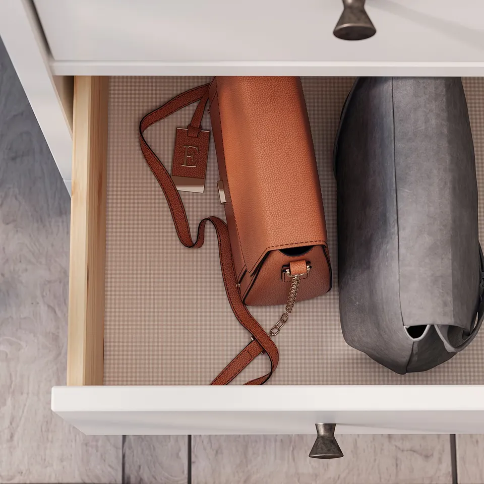 Brown leather handbag and grey backpack stored in drawer.