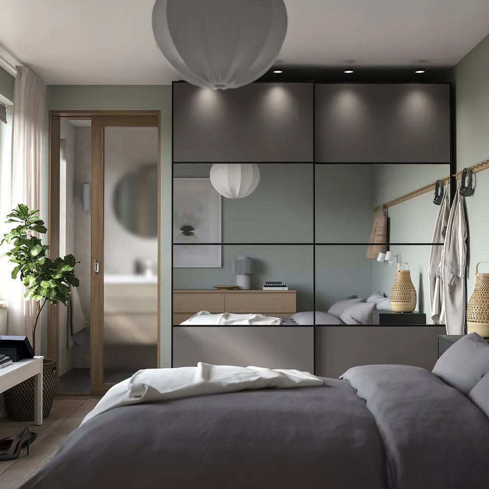 Modern bedroom with grey AULI mirrored and wood-patterned sliding doors, white bedding, hanging lights, and a plant near a wooden door.