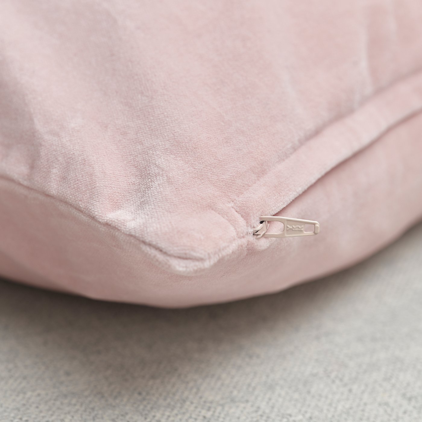 Close-up of pink velvet cushion zip, quality cotton fabric.