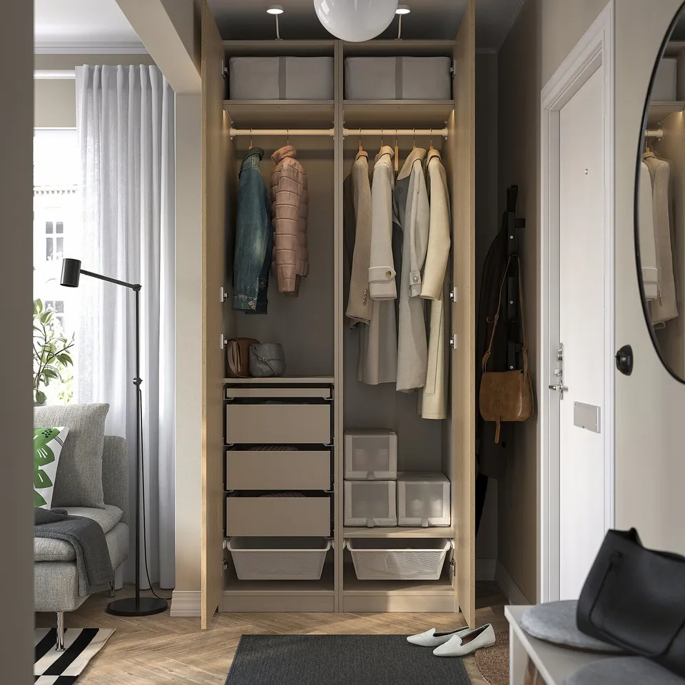 Open wooden wardrobe with clothes hangers, drawers, and boxes, showing storage and organisation inside a cosy room.