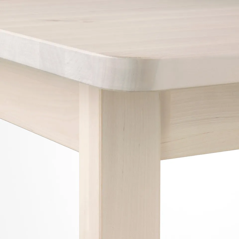 Light wooden table corner, smoothly rounded edges. Crafted with fine birch grain, its sturdy and stylish.