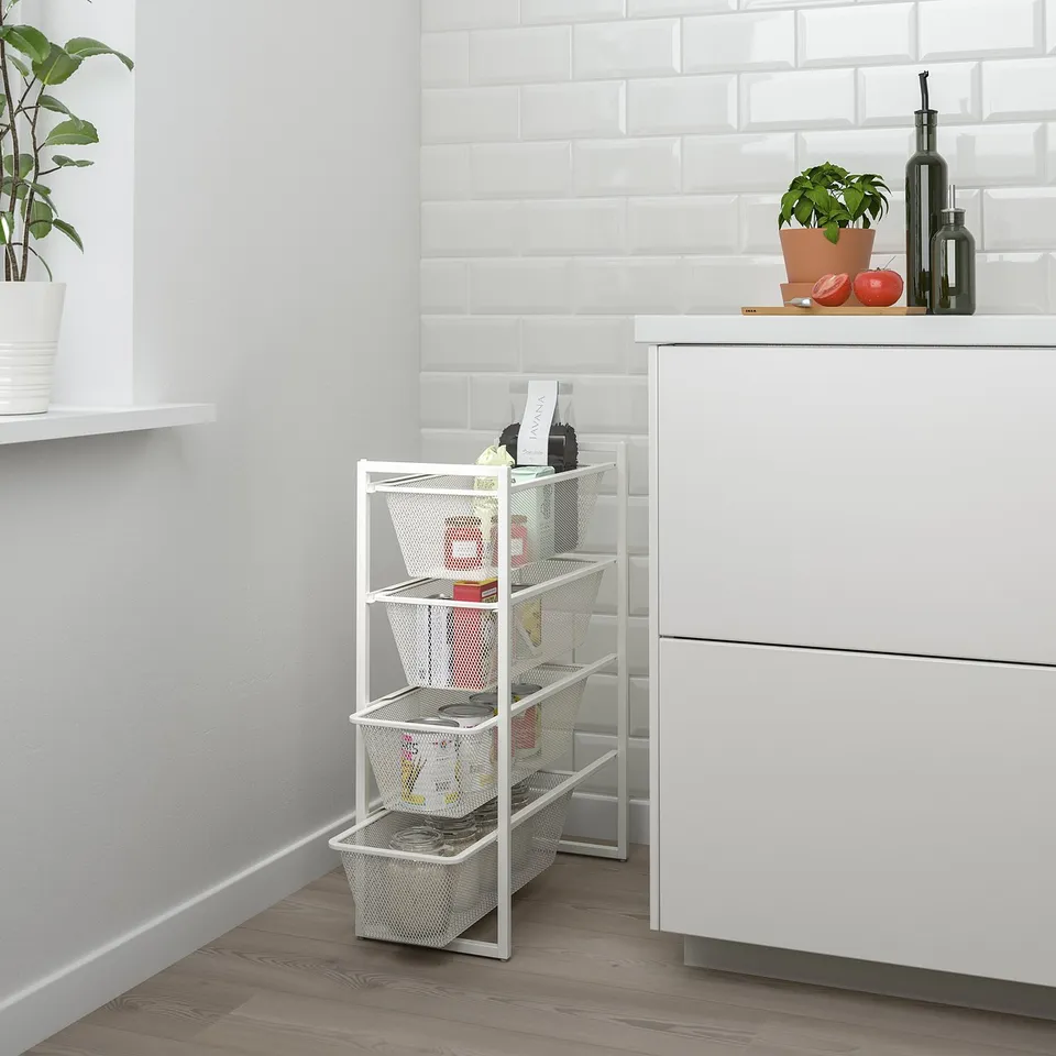 White JONAXEL storage shelf with four mesh baskets fits neatly in kitchen corner, holding various items.