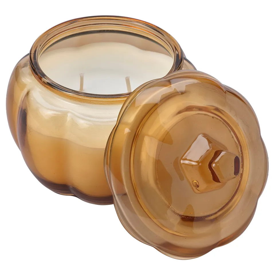 Amber glass pumpkin-shaped candle jar with lid, warm spiced scent, candle inside, decorative home decor.