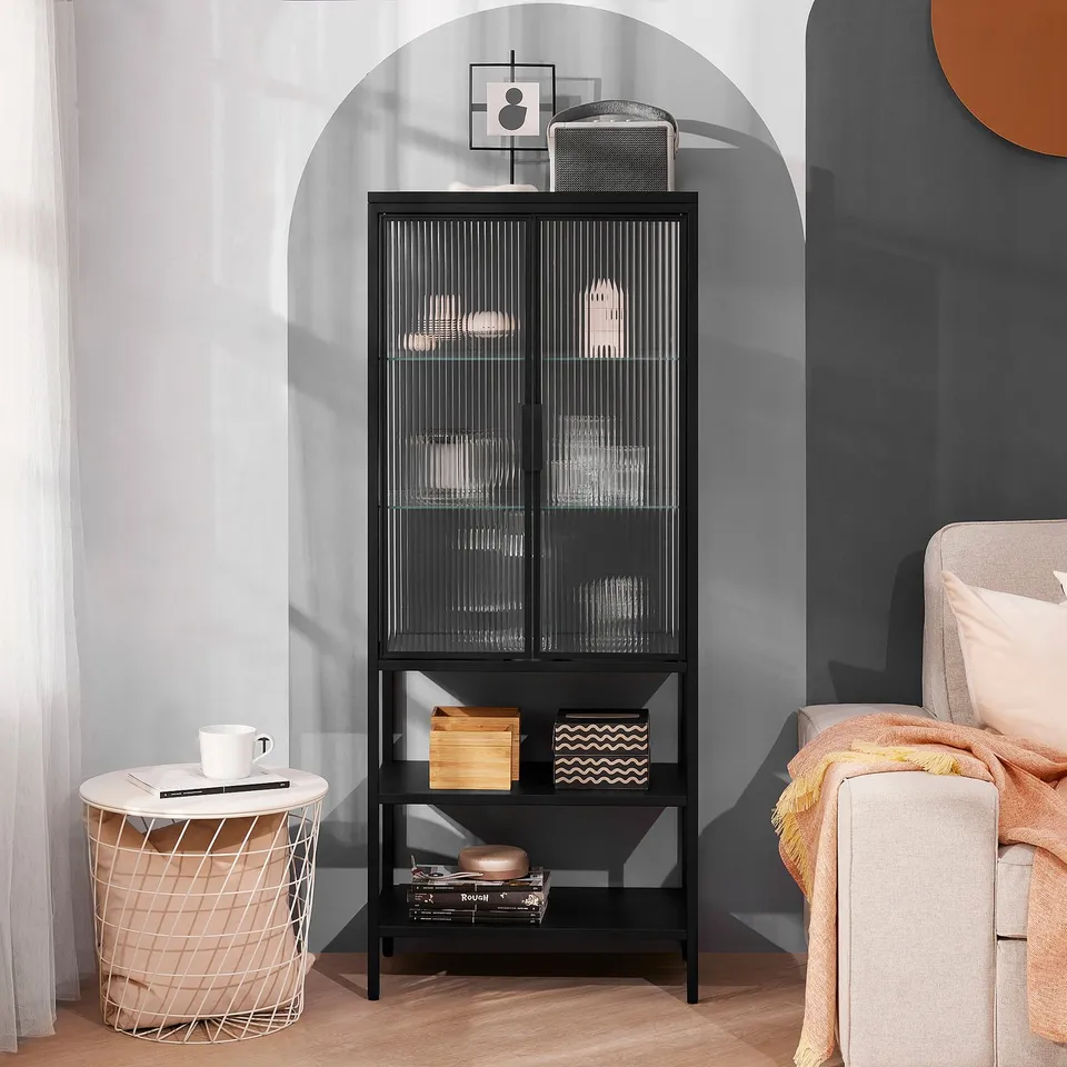 Black cabinet with reeded glass, decor. Beige side table, grey chair, peach blanket. Tall, arched alcove fit.