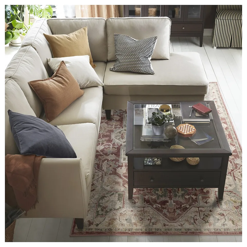 Modern living room with beige sofa, colourful pillows, coffee table, and ornate rug.