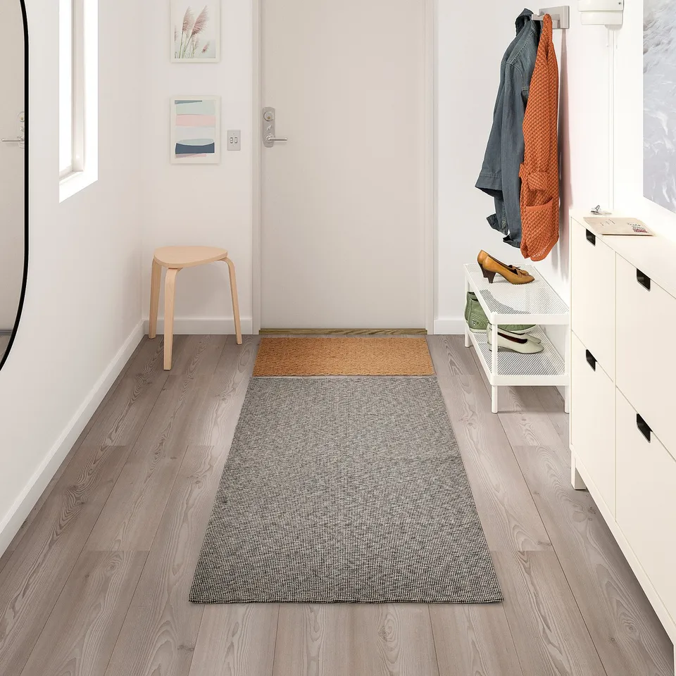 Light grey TIPHEDE rug with texture on wooden floor entryway.